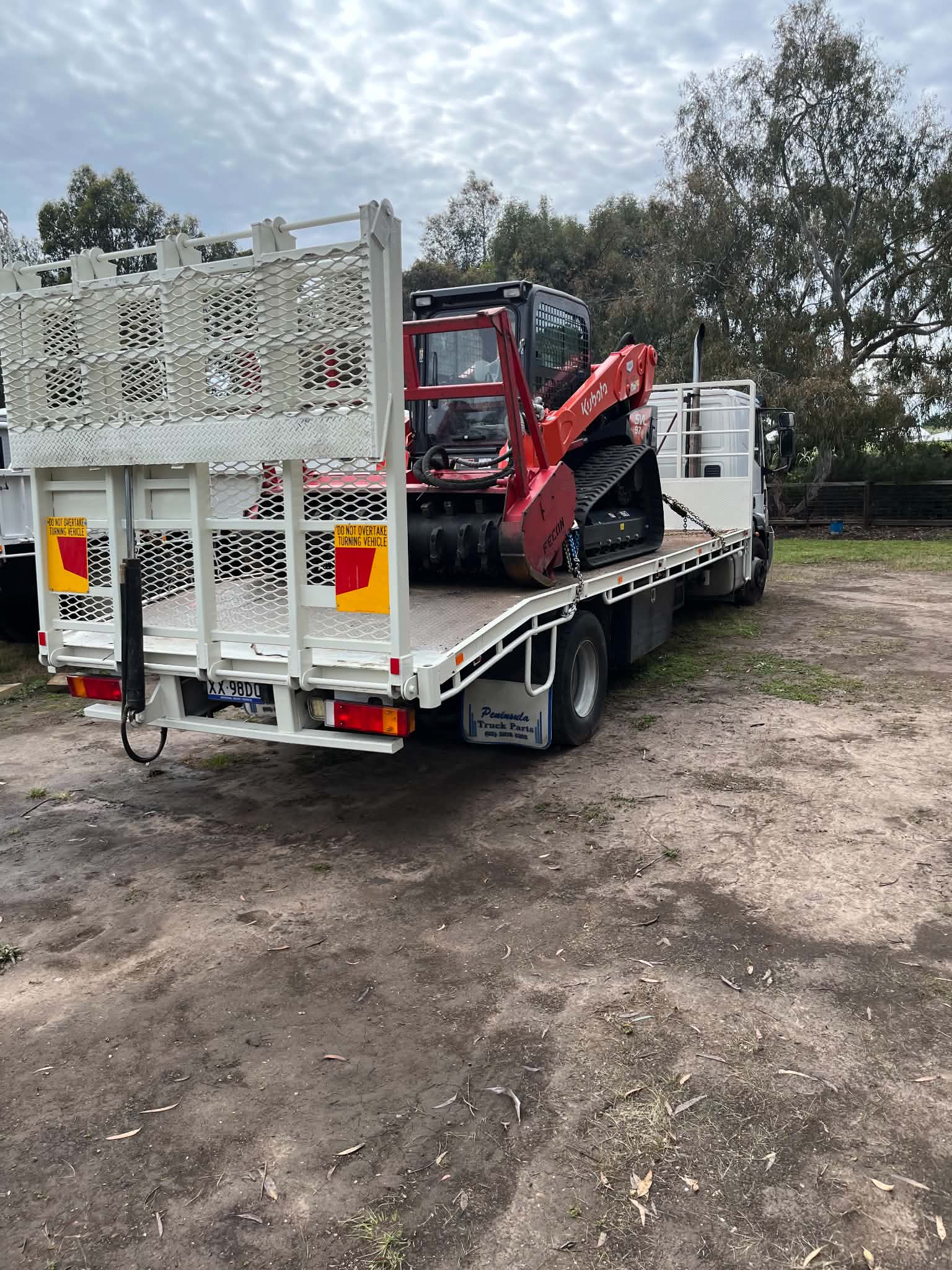 Beavertail truck carrying the forestry mulcher and skid steer